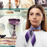 Woman wearing a purple geometric silk twill scarf with decorative background, of Buxton Museum with the Blue John stone.